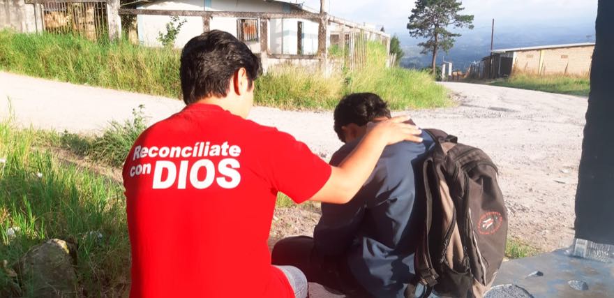 Un hermano ora por un joven en un camino de tierra